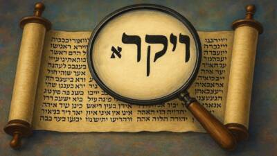 VAYIKRA in Torah scroll with magnifying glass enlarging the word and the tiny aleph