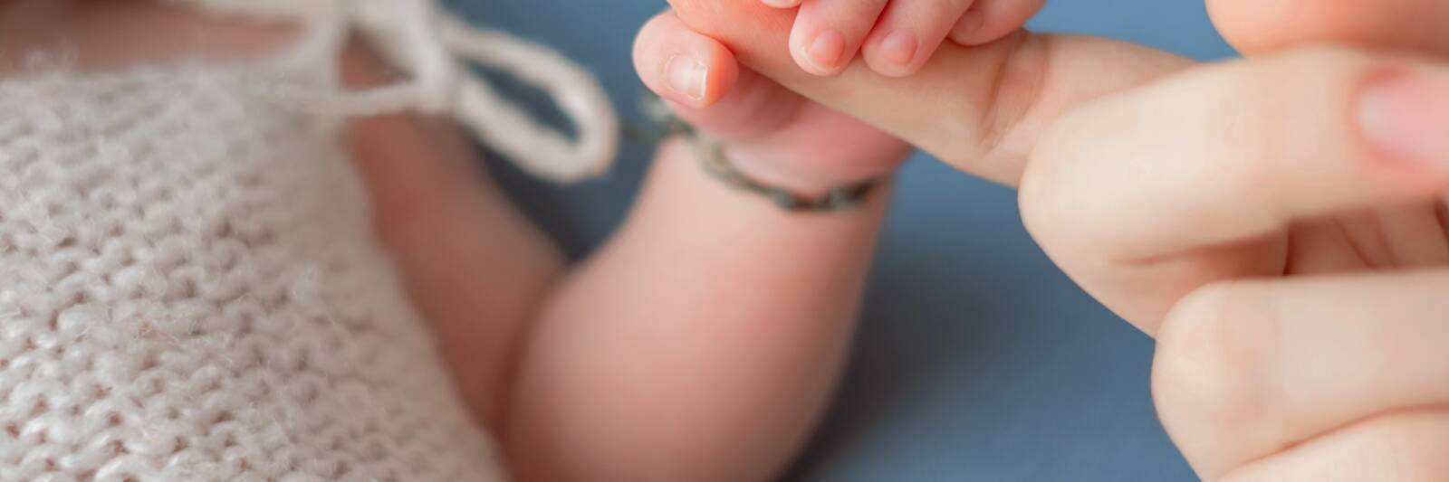 mother baby holding hands newborn fingers parent mum daughter 1
